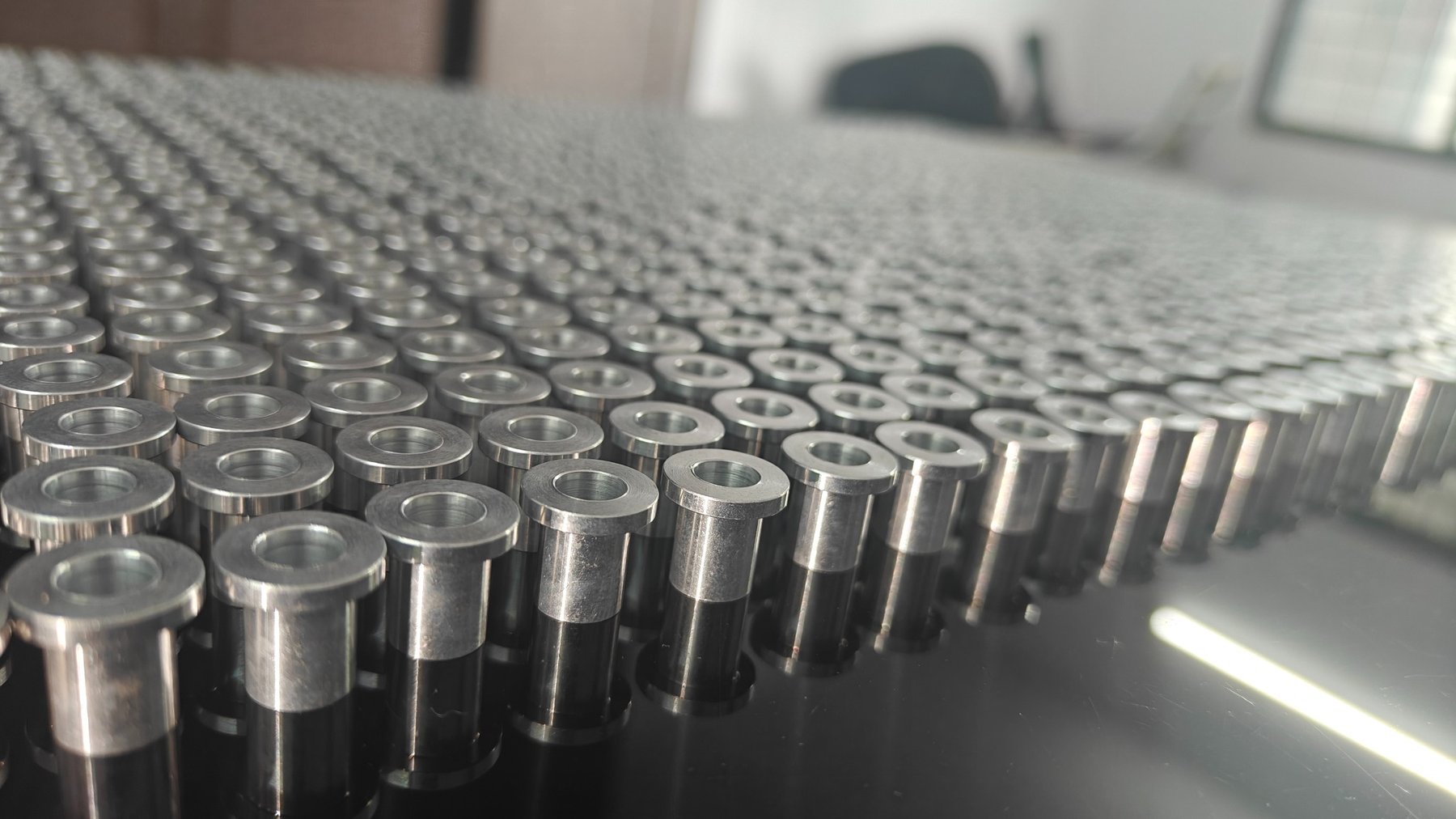 Large batch of precision turned components arranged in rows